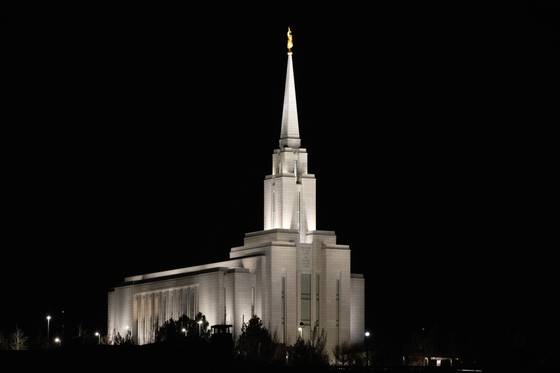 A lit temple spire against a black sky.