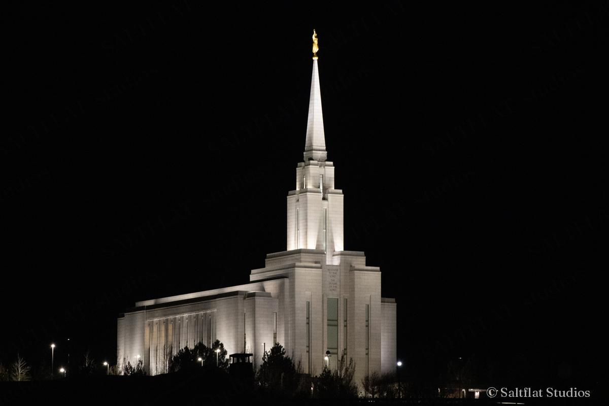 A lit temple spire against a black sky.