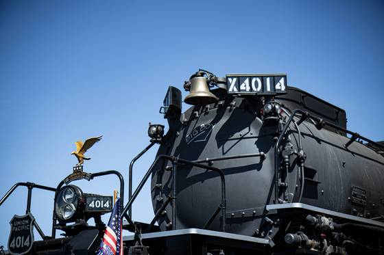 A black steam locomotive under a deep blue sky.