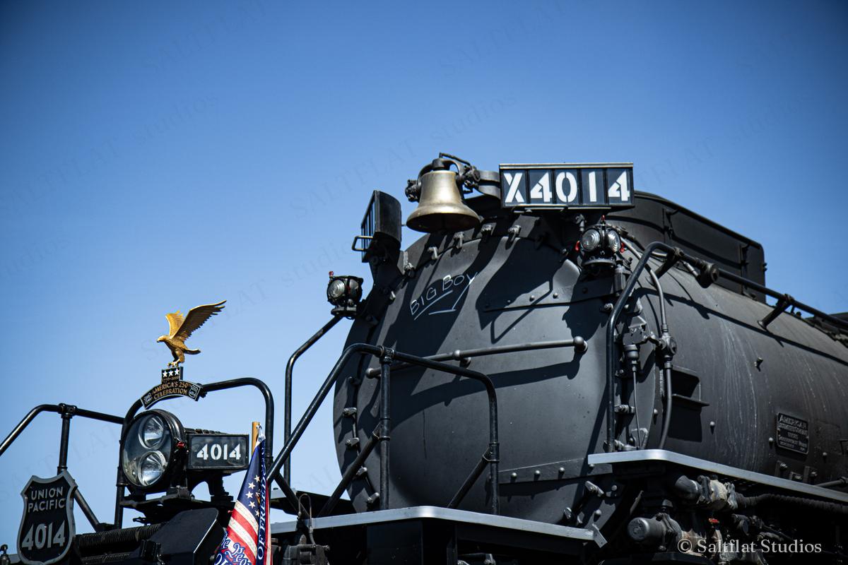 A black steam locomotive under a deep blue sky.