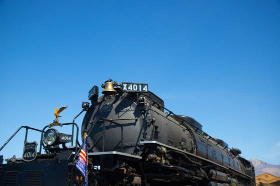 A steam locomotive from the side, under a deep blue sky.