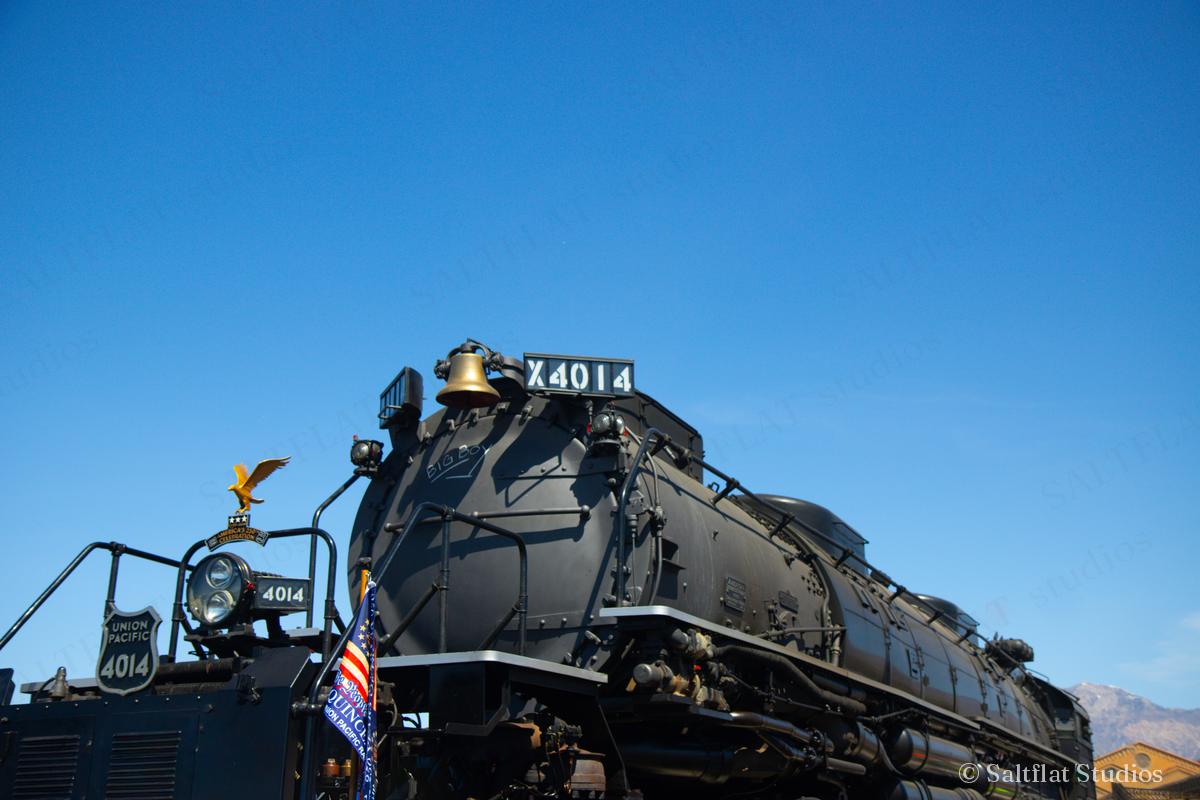 A steam locomotive from the side, under a deep blue sky.