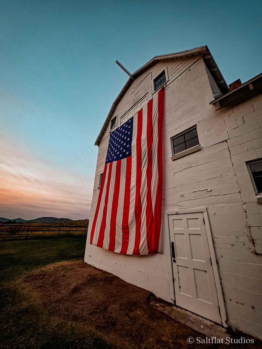 The white barn and flag in evening light.